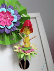 Bunte Handmade Dekofigur aus Papier und Holz mit Blüten und lachender Figur, ideal für kreative Bastelprojekte und Dekorationen.
