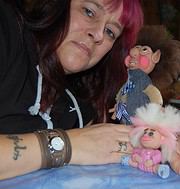 Frau mit pinkem Haar zeigt handgefertigte Puppen, kreative Handwerkskunst, DIY, Stoffpuppen, Handarbeit, kreative Bastelideen, Handmade Kultur, Kunsthandwerk, Puppenherstellung, kreative Geschenke.
