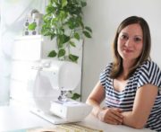 Frau sitzt an einer Nähmaschine in einem hellen, modernen Raum mit Pflanzen, ideal für kreative Handarbeit und Nähprojekte.