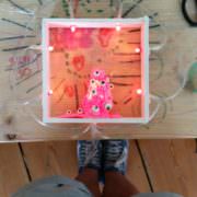 Kreatives Handmade-Projekt mit pinkem Monster aus Filz, umgeben von LED-Lichtern in einer Holzbox, ideal für DIY-Dekorationen und kreative Bastelideen.
