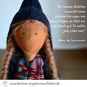 Handgefertigte Stoffpuppe mit langen Haaren, Mütze und buntem Kleid, begleitet von einem Zitat über Liebe und Fürsorge für Tiere, ideal für Handmade- und Puppenliebhaber.