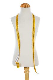 Gelbes Maßband, das um eine Schmuckpuppe drapiert ist, symbolisiert Handarbeit und kreatives Design, ideal für Handmade Kultur und DIY-Projekte.