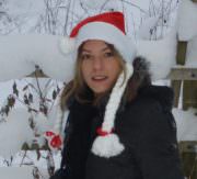 Frau trägt einen roten Santa-Hut mit weißen Bommel, umgeben von verschneiter Winterlandschaft, ideal für Weihnachts- und Handwerksdekorationen.