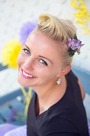 Fröhliche blonde Frau mit Blumen im Haar, strahlendes Lächeln, bei Handmade Kultur, kreative Handwerkskunst, Natur, Blumen, positive Stimmung, Mode, Lifestyle, Event, Kunst, Handarbeit.