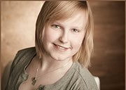Lächelnde junge Frau mit blonden Haaren, casual Kleidung und Herz-Halskette, bei HANDMADE Kultur, kreative Handwerkskunst, authentisches Porträt, freundliche Atmosphäre.