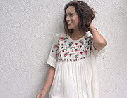 Frau trägt ein handgefertigtes Kleid mit floraler Stickerei, das kreative und nachhaltige Mode bei Handmade Kultur repräsentiert.