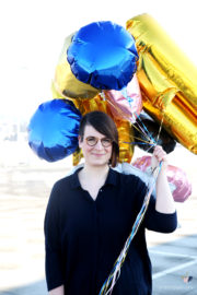 Frau hält bunte Luftballons, darunter blaue, goldene und pinke, bei HANDMADE Kultur Veranstaltung, fröhliche Atmosphäre, kreative Feier, festliche Dekoration.