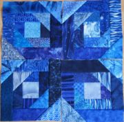 Detailaufnahme eines handgefertigten Quilt-Blocks mit verschiedenen blauen Stoffmustern und geometrischen Formen, kunstvoll zusammengenäht für ein einzigartiges Quilt-Design.