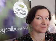 Porträt einer Frau bei der HANDMADE Kultur mit einem Banner von Tigerflikka of Sweden im Hintergrund, Fokus auf handgemachte Produkte und kreative Handwerkskunst.