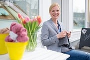 Frau bei Handmade Kultur zeigt kreative Handwerkskunst, umgeben von bunten Blumen und handgemachten Produkten, ideal für DIY- und Bastelenthusiasten.