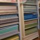 Verschiedene Stoffe und Nähzubehör in einem weißen Regal bei HANDMADE Kultur, ideal für kreative Nähprojekte und handgemachte Textilkunst.