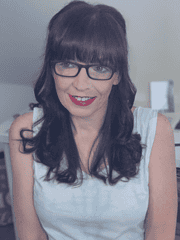 Frau mit dunklen Haaren, Brille und rotem Lippenstift, die kreative Handwerkskunst präsentiert, bei HANDMADE Kultur, Fokus auf handgemachte Produkte und kreative Gemeinschaft.