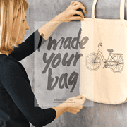 Person hält eine Stofftasche mit dem Aufdruck "I made your bag" und Fahrradzeichnung, Fokus auf handgemachte Produkte und nachhaltige Mode.