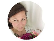 Nahaufnahme einer Frau mit dunklem Haar, die ein Bouquet aus bunten Blumen hält, symbolisiert kreative Handarbeit und Kunsthandwerk bei Handmade Kultur.