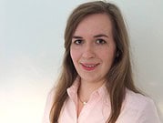 Porträt einer jungen Frau mit braunen Haaren, die ein hellrosa Hemd trägt, vor einem weißen Hintergrund, geeignet für handgemachte Kultur und kreative Projekte.