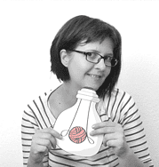 Frau mit Brille hält eine handgemachte Bastelarbeit in Form einer Flasche mit Wollknäuel und Garn, kreative Handwerkskunst für DIY-Projekte bei Handmade Kultur.