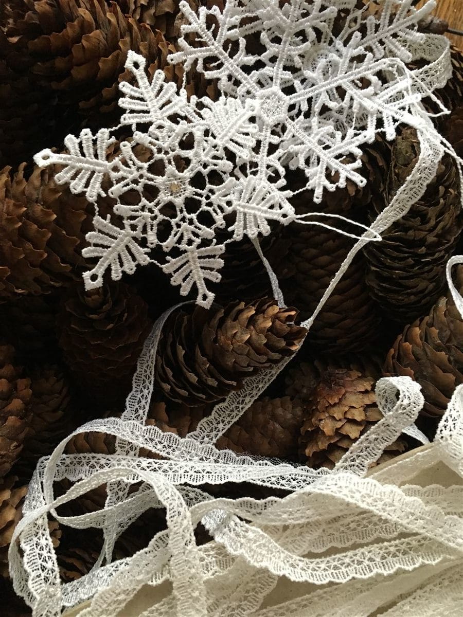 weihnachtliche Türdeko aus Tannenzapfen und Spitze