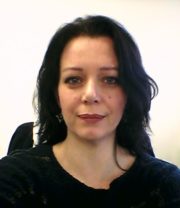 Porträt einer Frau mit dunklem Haar, die handgemachte Kunstwerke präsentiert, symbolisiert kreative Handwerkskunst und nachhaltiges Design bei Handmade Kultur.