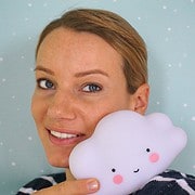 Lächelnde Frau hält ein weiches, niedliches Cloud-Kissen mit Gesicht, ideal für Kinderzimmer und als Geschenk bei Handmade Kultur.