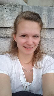 Porträt einer jungen Frau mit freundlichem Lächeln, braunen Haaren und weißem Blusen, ideal für Handmade- und Kulturthemen, authentisch und ansprechend.