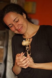 Frau hält liebevoll eine handgefertigte Stoffgiraffe, die mit bunten Mustern gestaltet ist, ideal für handgemachte Dekorationen und Geschenke.