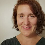 Porträt einer lächelnden Frau mit kurzen braunen Haaren, die handgemachte Kunst und kreative Arbeiten repräsentiert, passend für die Themen Handmade und Kultur.