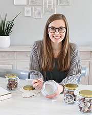 Junge Frau mit Brille zeigt selbstgemachte Bastelarbeiten und kreative Dekorationen für Handmade Kultur, umweltfreundlich und individuell gestaltet.