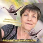 Fotografie einer Frau mit Origami-Kranichen aus Papier, die kreative Handwerkskunst und Origami-Kunst zeigt, passend für Handmade- und Bastelthemen.