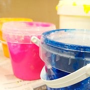 Verschiedene bunte Kunststoffbehälter mit Mal- und Bastelmaterialien für kreative Handwerksprojekte bei HANDMADE Kultur.