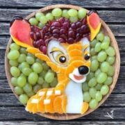 Kreative Obstdekoration in Form eines Drachen, bestehend aus Trauben, Melone, Mango und anderen Früchten, kunstvoll arrangiert für handgemachte Kunstwerke.