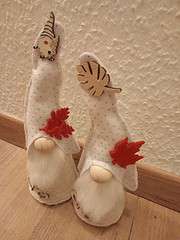 Zwei handgefertigte Weihnachtswichtel aus Stoff mit roten Filzblättern, Holz- und Filzdekorationen, ideal für festliche Dekorationen bei HANDMADE Kultur.