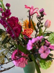 Verschiedene bunte Schnittblumen in einem grünen Vase, inklusive Rosen, Nelken, Lilien und Hortensien, für eine lebendige und kreative Blumenarrangement-Dekoration.