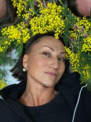 Blumenkranz mit gelben Mimoseblumen und grünen Blättern, auf dem Gesicht einer Frau liegend, bei HANDMADE Kultur.