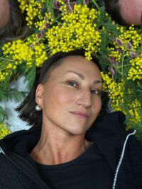 Blumenkranz mit gelben Mimoseblumen und grünen Blättern, auf dem Gesicht einer Frau liegend, bei HANDMADE Kultur.