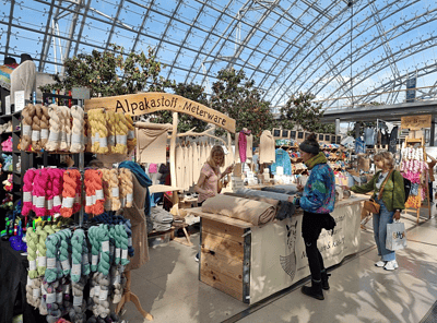 Handmade Kultur Markt im Gewächshaus, Verkauf von Alpakawolle, Strickwaren und naturbelassenen Textilien, handmade, regional, nachhaltige Mode und Handwerkskunst, kreative Kunsthandwerksmesse.