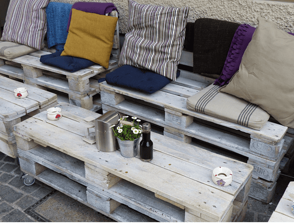 Vintage Palettenmöbel mit bunten Kissen und Dekoration, nachhaltiges DIY-Mobiliar, kreative Upcycling-Ideen für Garten und Terrasse, handgemacht für gemütliches Ambiente.