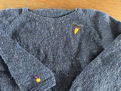 Bergfummel gestrickter Pullover mit bunter Biene Stickerei, handgemacht, in dunkelblauer Farbe, kuschelige Wintermode, skandinavischer Stil, Nachhaltige Handarbeit, nachhaltige Mode, handgefertigte Textilien, modische Strickwaren, Wollpullover.