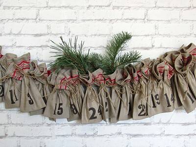 Adelgsam gestaltete DIY Adventskalender-Säckchen aus Jute mit Zahlen, belebt mit Tannenzweigen, für nachhaltige Weihnachtsdeko.