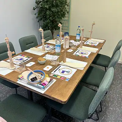 Farbenfrohe Näh-Workshop-Sitzung mit Werkzeugen, Stoffen und Garnen auf einem Holztisch, ideal für kreative Handarbeit und DIY-Projekte in einer inspirierenden Umgebung.