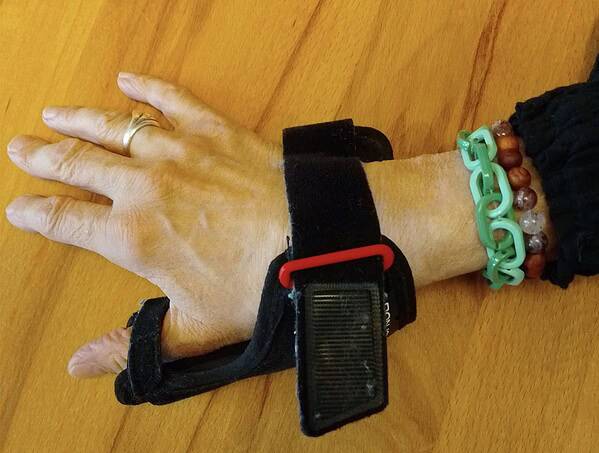 Menschliche Hand mit bunten Schmuck- und Armbändern, zeigt handgemachte Kultur und Kreativität, Fokus auf DIY, Accessoires und handgefertigte Schmuckstücke, auf Holzoberfläche.