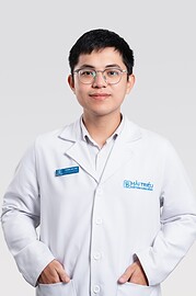 Arzt in Weiß mit Brille und Name Badge, professionell und freundlich, symbolisiert medizinische Kompetenz und Vertrauen bei HANDMADE Kultur.