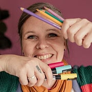 Junge Frau zeigt kreative Handarbeit mit bunten Stiften und Filzstiften, Freude an DIY-Projekten, handgemachte Kunst und Bastelideen, für Handmade Kultur Website.