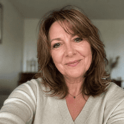 Frau mit braunen Haaren und freundlichem Lächeln, trägt helles Oberteil, in einem gemütlichen Raum, ideal für handgemachte Kultur und kreative Projekte.