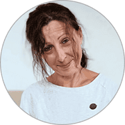 Frau mit lockigem braunem Haar, freundlichem Lächeln, trägt weißes T-Shirt mit HANDMADE Kultur Logo, authentisch, kreative Handwerkskunst, nachhaltige Produkte, handgemacht, Kunsthandwerk.