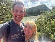 Zwei glückliche Menschen in einer natürlichen Umgebung mit Wasser und Bäumen, ideal für Handmade Kultur Themen, Natur, Outdoor, Freude, Gemeinschaft.
