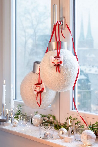 Zwei XXL-Weihnachtskugeln aus Kunstschnee mit rotem Band und Raffaello